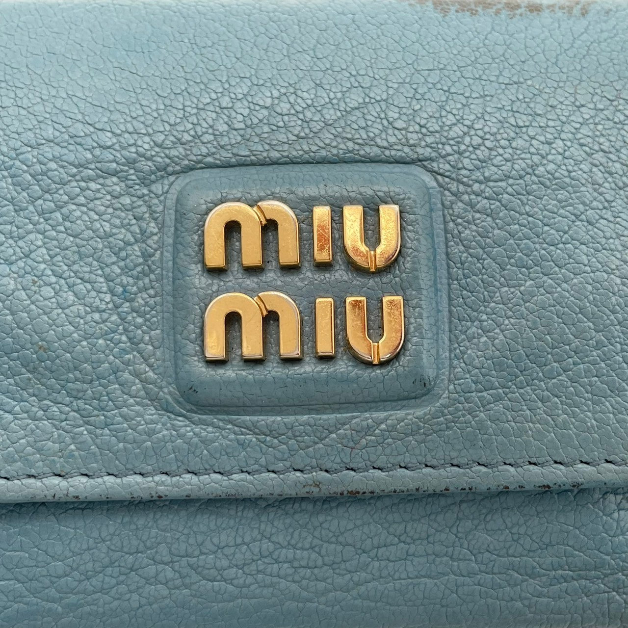 良品 ミュウミュウ miumiu 三つ折り財布 折り財布 コンパクトウォレット ミニ財布 マドラス レザー 本革 ライトブルー 水色 メタルロゴ ゴールド金具 レディース エレガント キュート フェミニン カジュアル デイリー 通勤 通学 上品 大人 W1